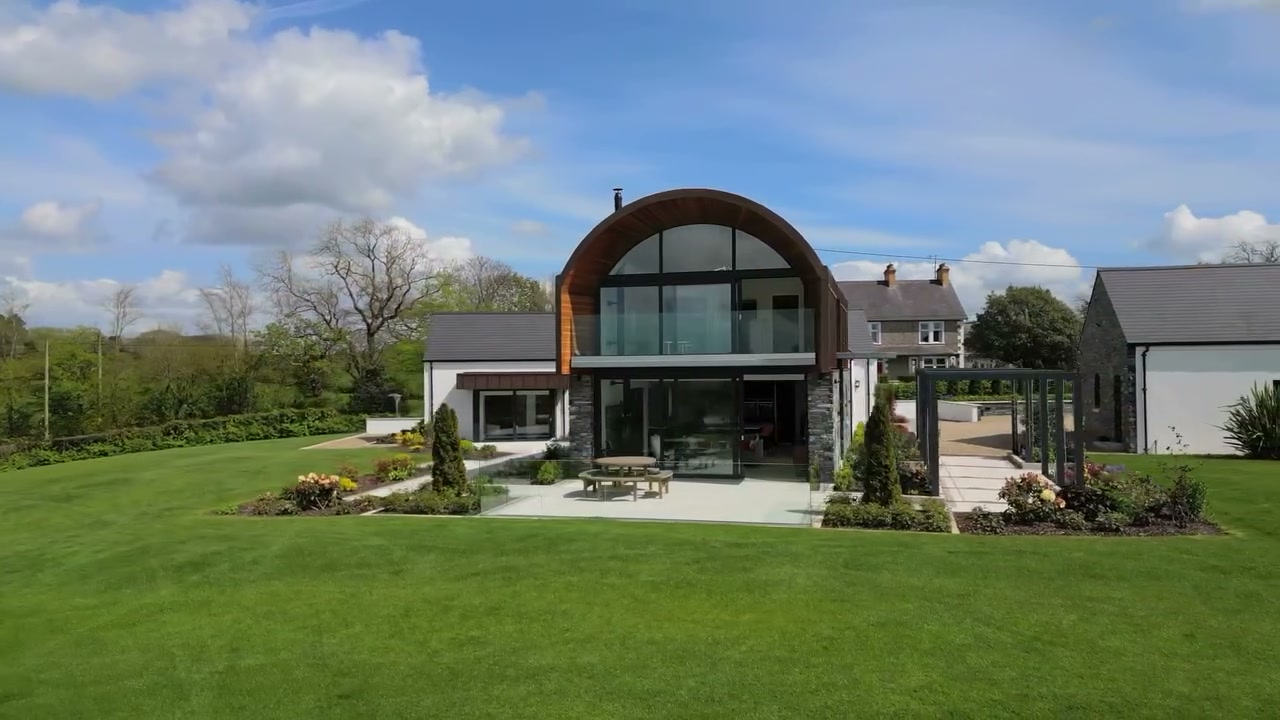 Phantom property film still of a contemporary barn-style home with dark cladding and full-height glazing near Lisburn