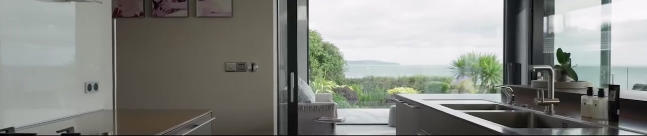 Cinematic Phantom film still of a glass-fronted five-bedroom coastal residence at Grey Point, Helen's Bay, with uninterrupted views over Helen's Bay Beach